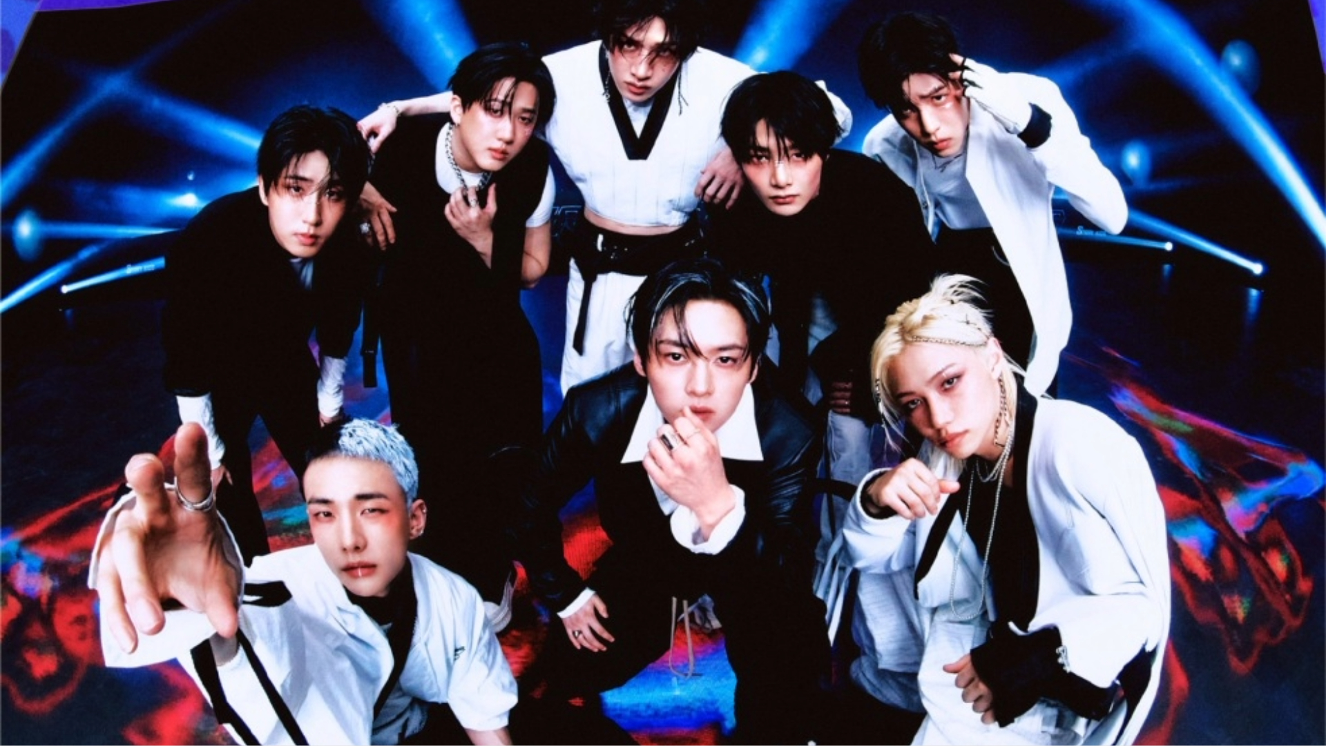 Grupo Stray Kids posando em estúdio com iluminação futurista, vestindo roupas em preto e branco, em foto promocional de 2024.