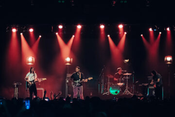 Terno Rei ao vivo em São Paulo durante show de encerramento da turnê, com iluminação vermelha e público lotado.