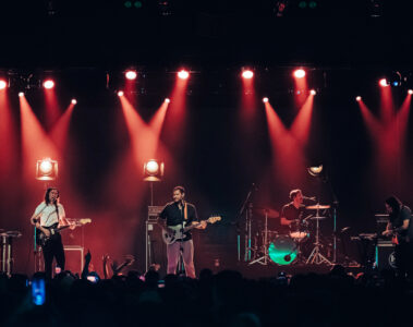 Terno Rei ao vivo em São Paulo durante show de encerramento da turnê, com iluminação vermelha e público lotado.