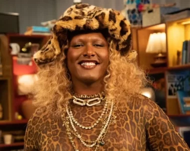 Liniker sorrindo em estúdio do Tiny Desk Brasil, usando chapéu e roupa com estampa animal print, durante gravação do episódio com música inédita.