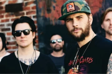 Banda Avenged Sevenfold posando ao ar livre, com M. Shadows em destaque usando boné camuflado.