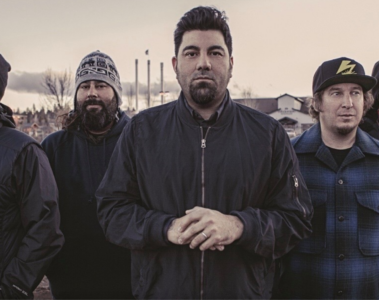 Foto da banda Deftones reunida ao ar livre, com Chino Moreno ao centro e os demais integrantes posando de casacos em clima frio.