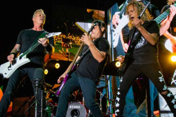 James Hetfield, Robert Trujillo e Kirk Hammett tocando ao vivo durante show do Metallica.