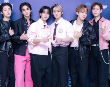 Foto do grupo Stray Kids posando juntos em evento, usando roupas em tons de preto e rosa — X/Reprodução.