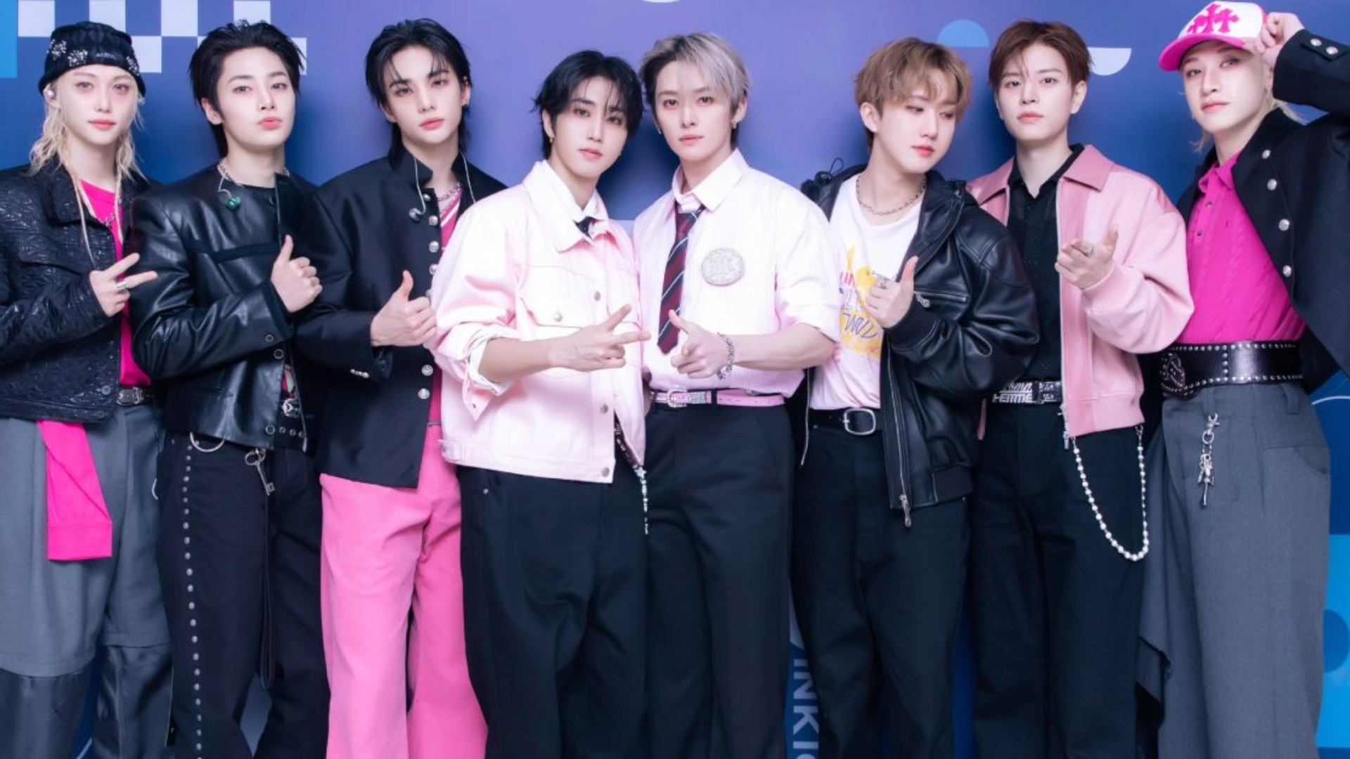 Foto do grupo Stray Kids posando juntos em evento, usando roupas em tons de preto e rosa — X/Reprodução.