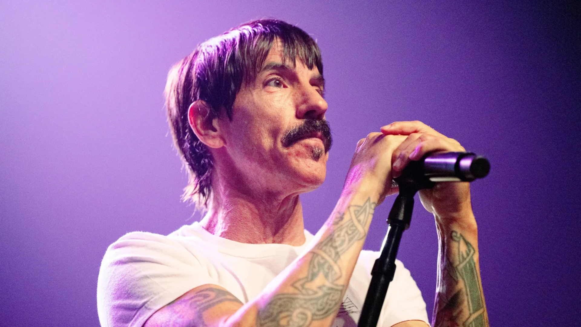 Anthony Kiedis durante show do Red Hot Chili Peppers segurando o microfone no palco