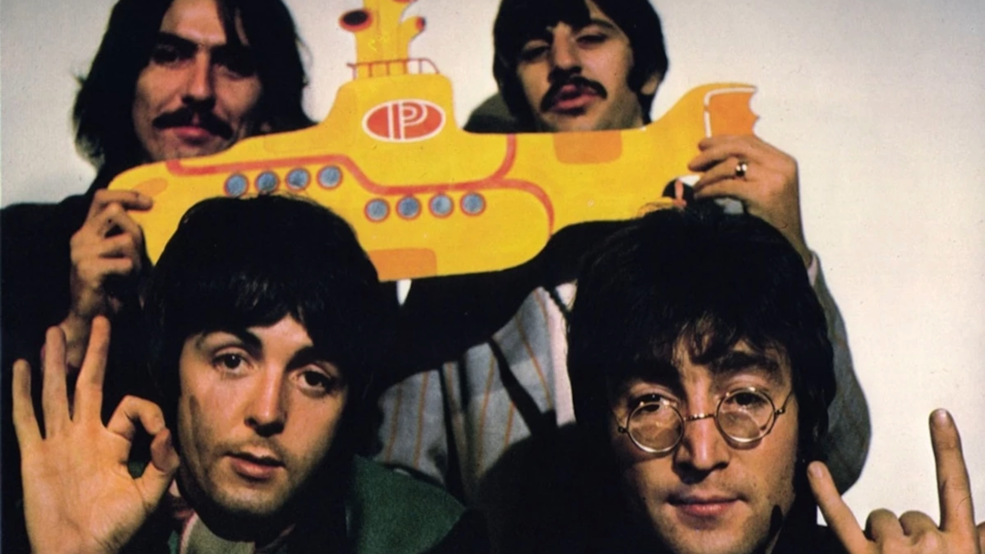 The Beatles segurando um submarino amarelo durante a era do álbum Yellow Submarine, em imagem promocional dos anos 1960