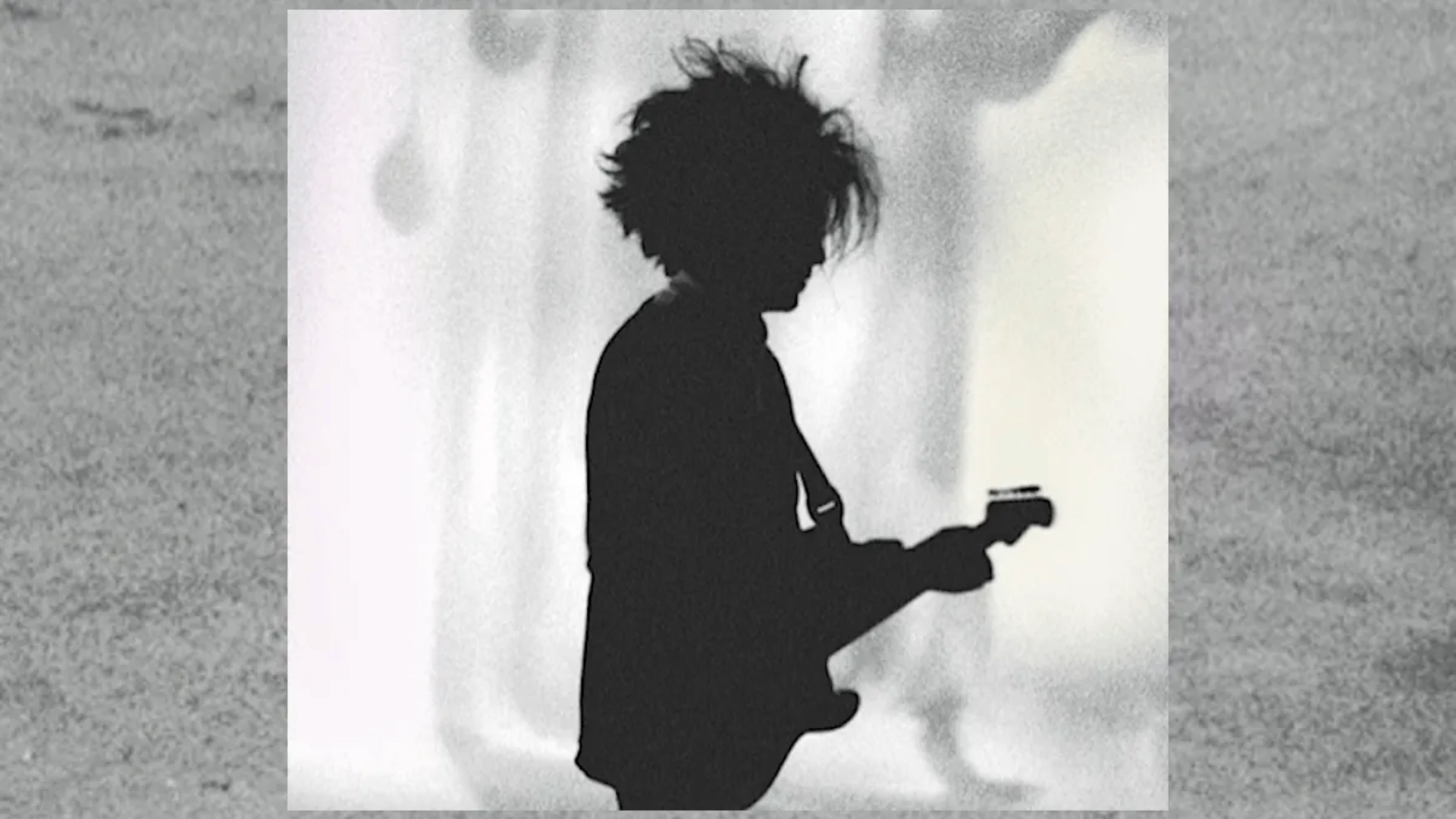 Silhueta de Robert Smith tocando guitarra em imagem associada ao single “Boys Don’t Cry”, do The Cure