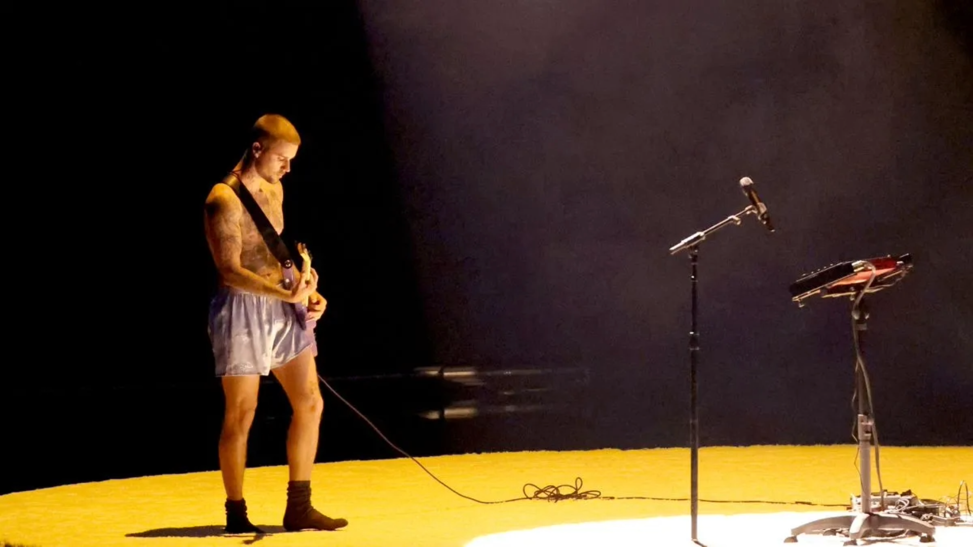 Justin Bieber durante apresentação no Grammy Awards 2026, tocando guitarra em performance minimalista.