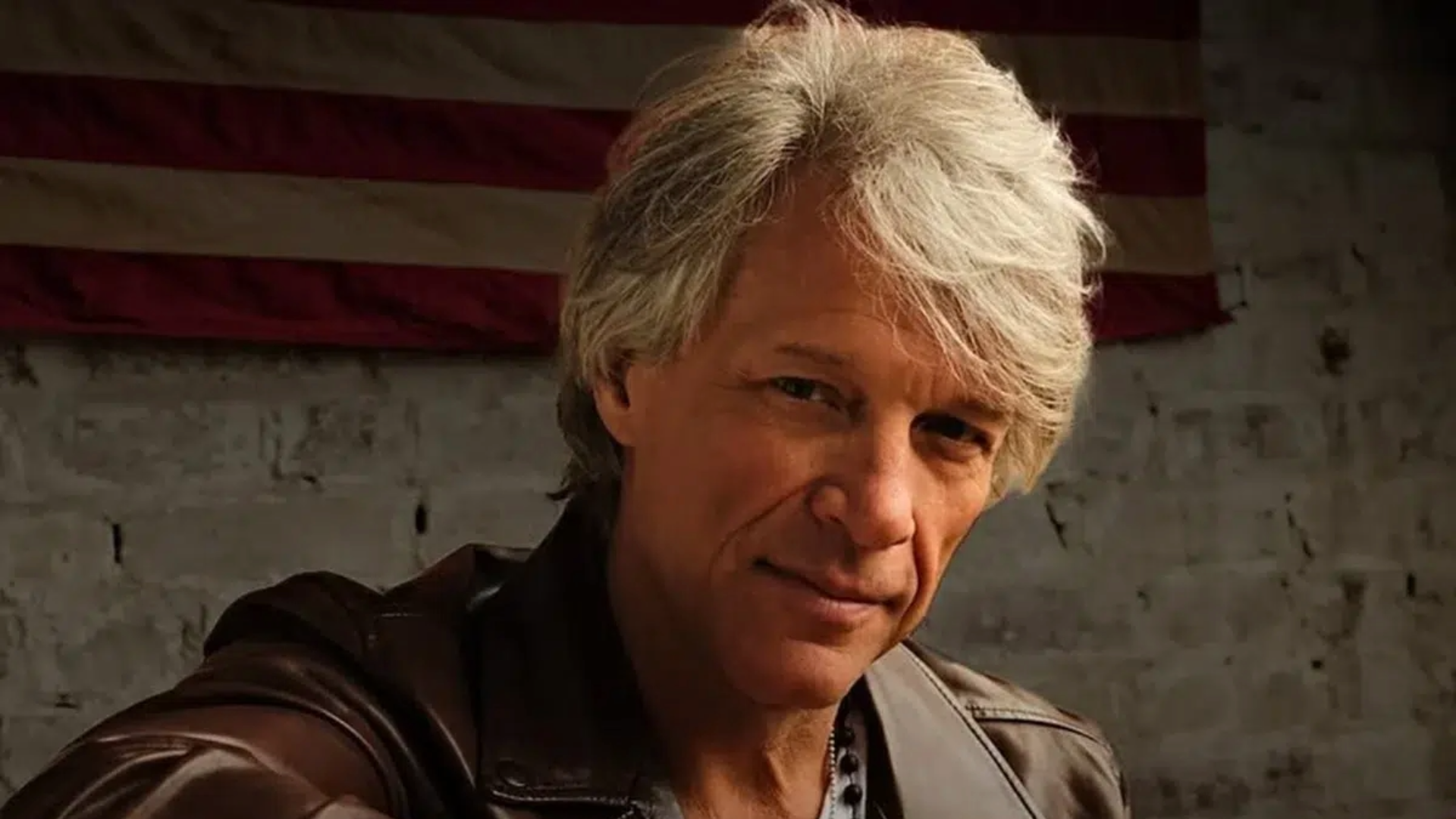 Jon Bon Jovi em retrato promocional durante fase solo, usando jaqueta de couro.