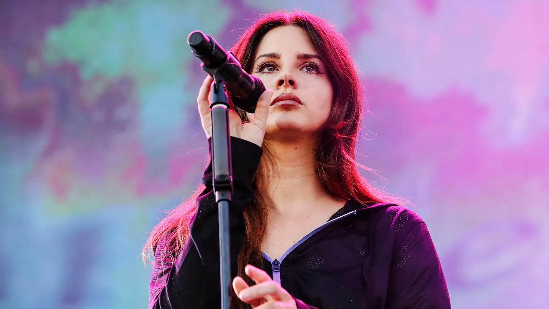 Lana Del Rey cantando ao vivo em show, com microfone no palco