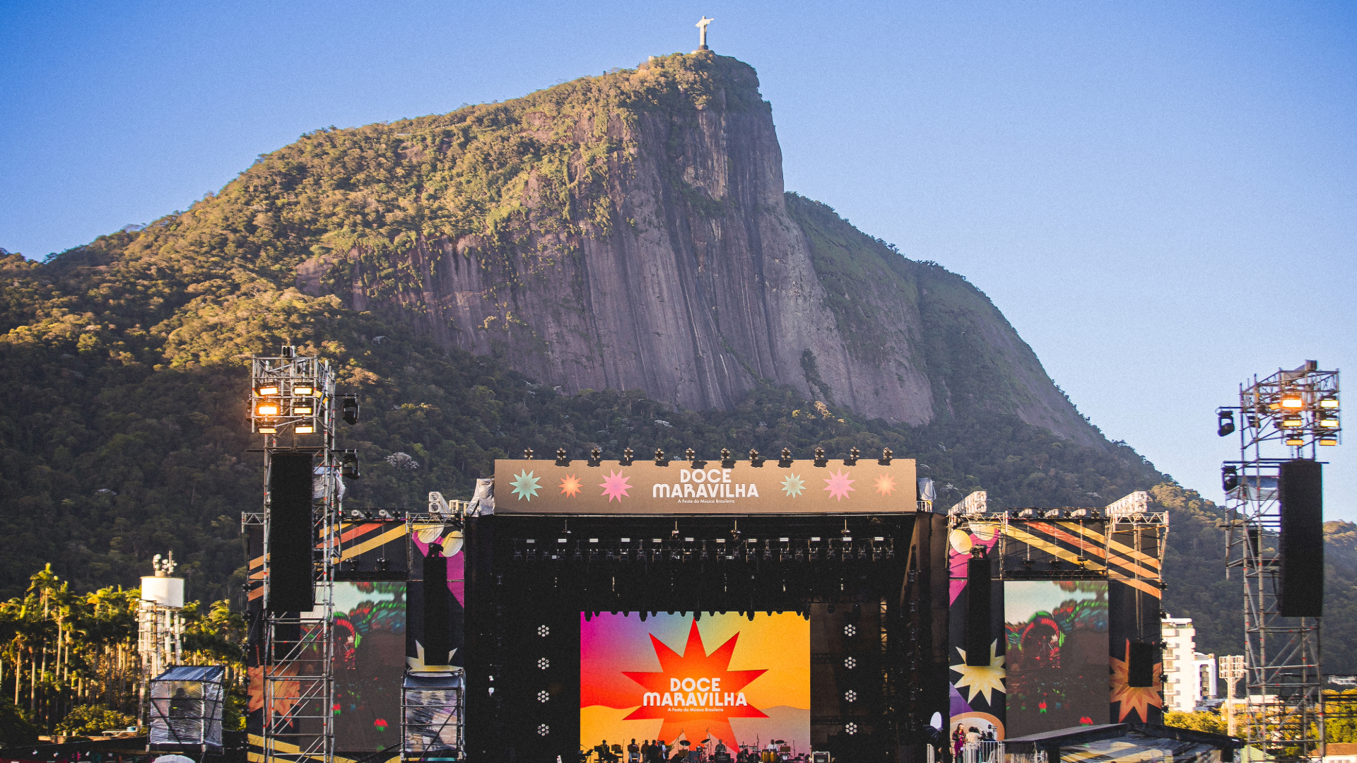 Palco do festival Doce Maravilha com público no Jockey Club e Cristo Redentor ao fundo no Rio de Janeiro