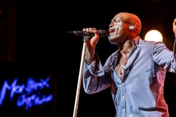 Seal cantando ao vivo em show com microfone e iluminação de palco durante turnê internacional