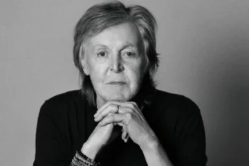 Paul McCartney em retrato preto e branco com as mãos apoiadas no queixo