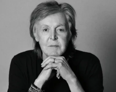 Paul McCartney em retrato preto e branco com as mãos apoiadas no queixo