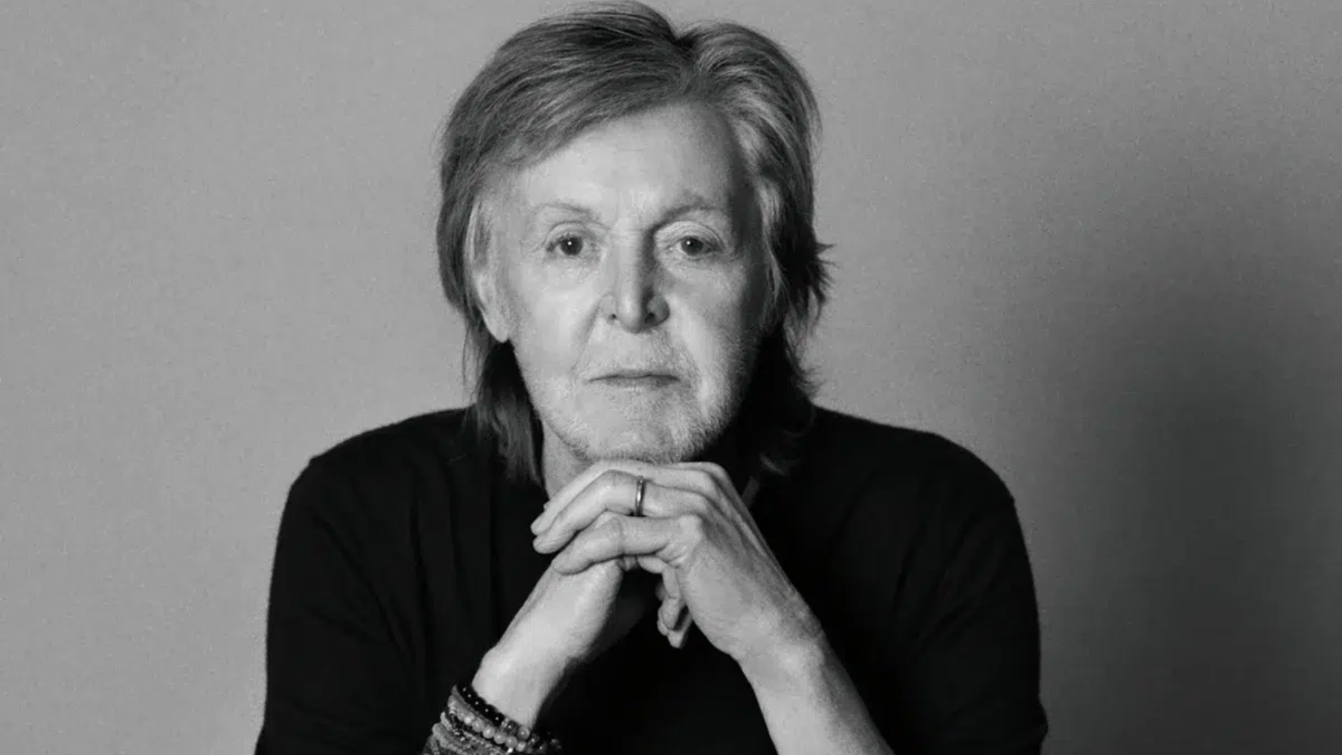 Paul McCartney em retrato preto e branco com as mãos apoiadas no queixo
