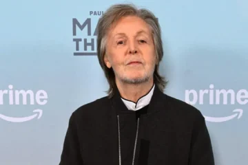 Paul McCartney em evento promocional com fundo azul e logo do Prime Video