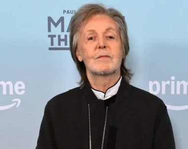 Paul McCartney em evento promocional com fundo azul e logo do Prime Video