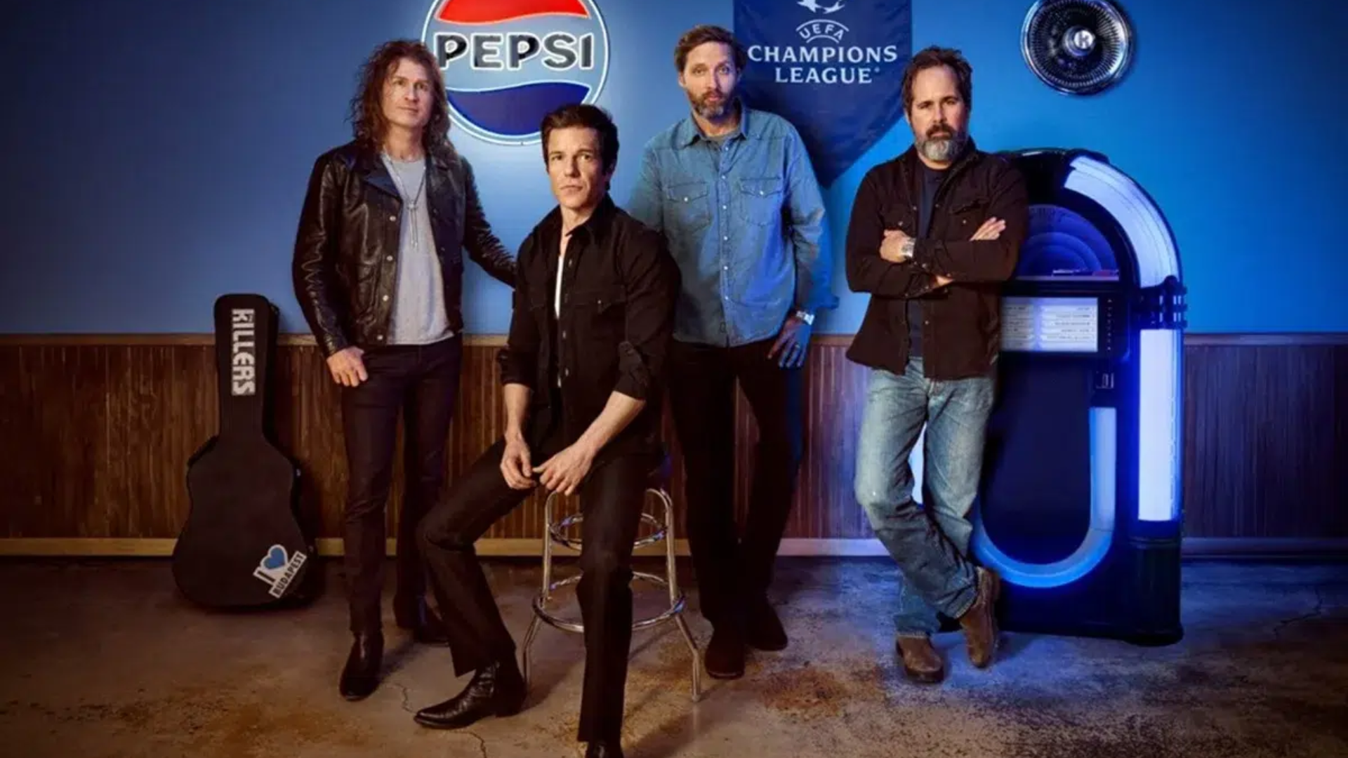 The Killers posando em estúdio com logo da Pepsi e Champions League ao fundo