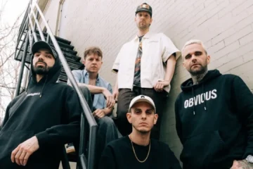 Banda francesa LANDMVRKS posando em escada externa antes de show; grupo de metalcore anuncia estreia no Brasil em 2026