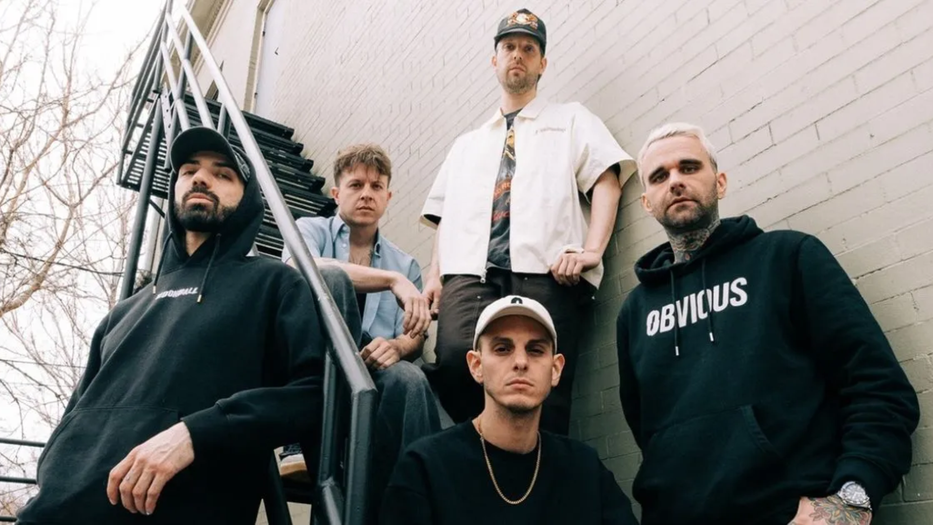 Banda francesa LANDMVRKS posando em escada externa antes de show; grupo de metalcore anuncia estreia no Brasil em 2026
