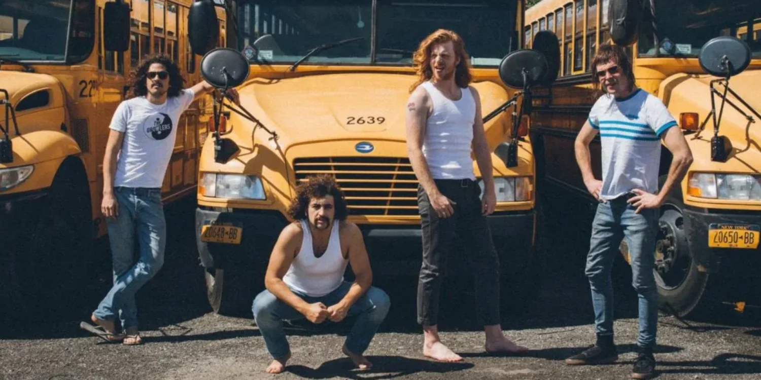 banda Sticky Fingers posando em frente a ônibus amarelos durante divulgação de turnê