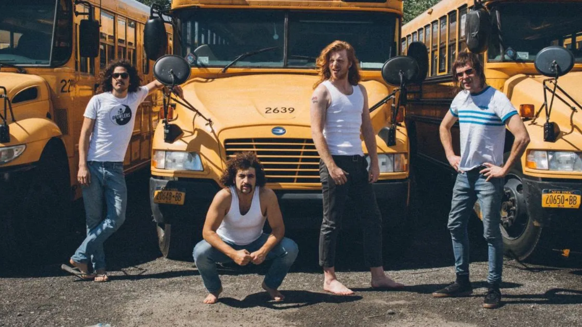 banda Sticky Fingers posando em frente a ônibus amarelos durante divulgação de turnê