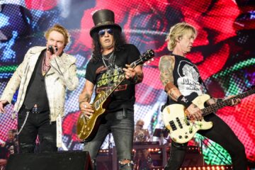 Axl Rose, Slash e Duff McKagan em show do Guns N’ Roses no palco com iluminação colorida