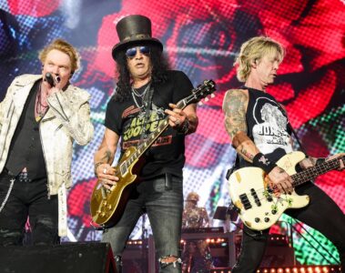 Axl Rose, Slash e Duff McKagan em show do Guns N’ Roses no palco com iluminação colorida