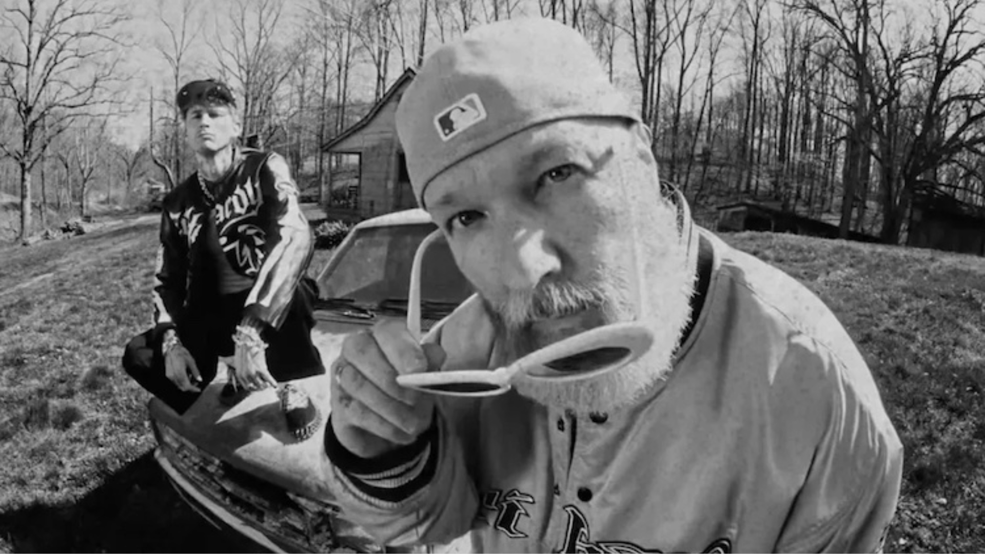 Machine Gun Kelly e Fred Durst em cena de videoclipe em preto e branco para a música “FIX UR FACE”, com estética crua e visual urbano.