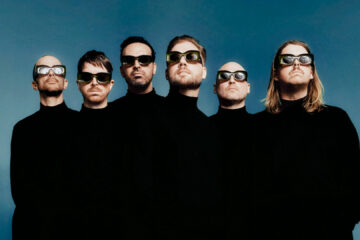 Integrantes da banda LEISURE usam roupas pretas e óculos futuristas em foto promocional da turnê Welcome To The Mood