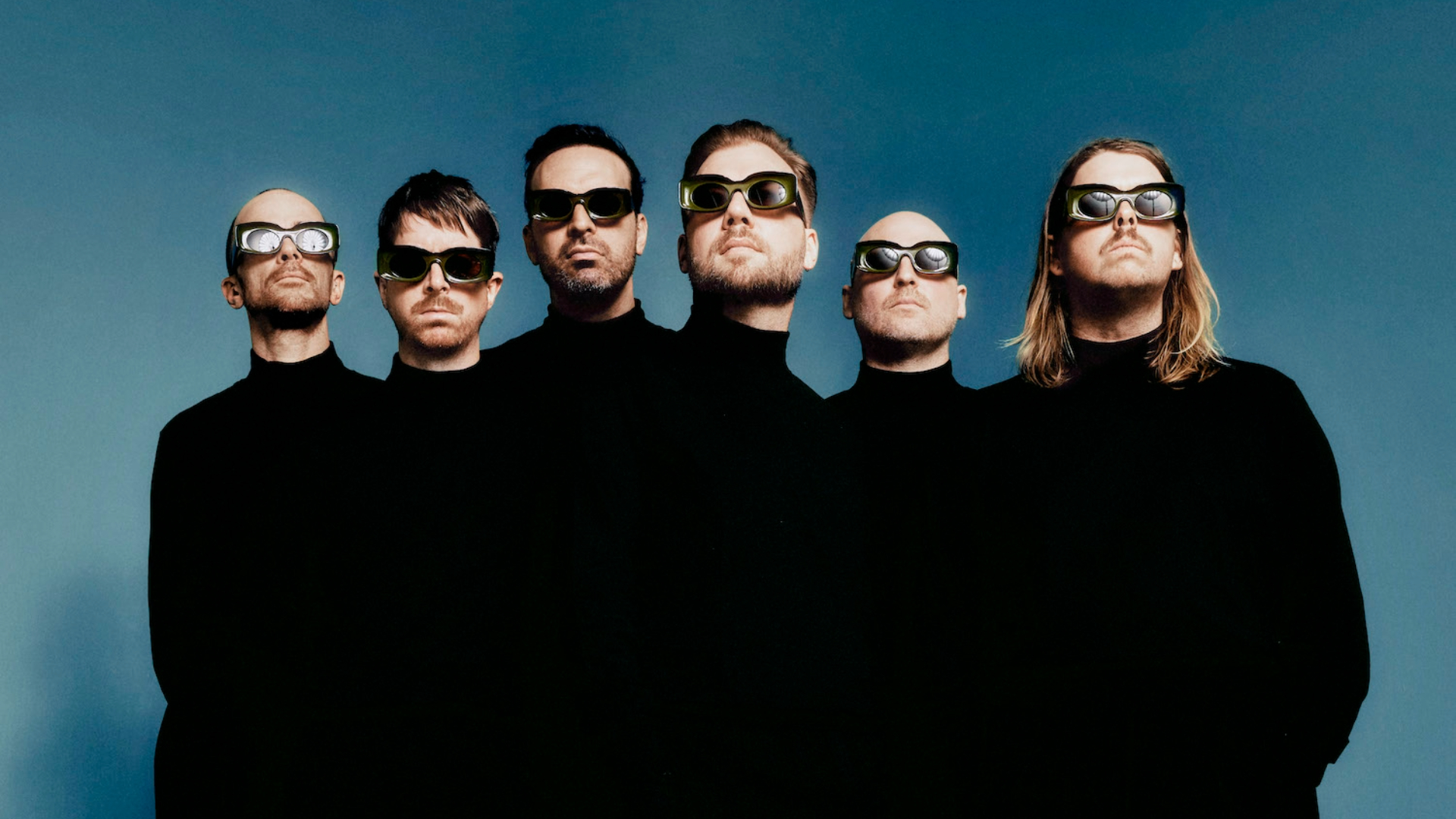 Integrantes da banda LEISURE usam roupas pretas e óculos futuristas em foto promocional da turnê Welcome To The Mood