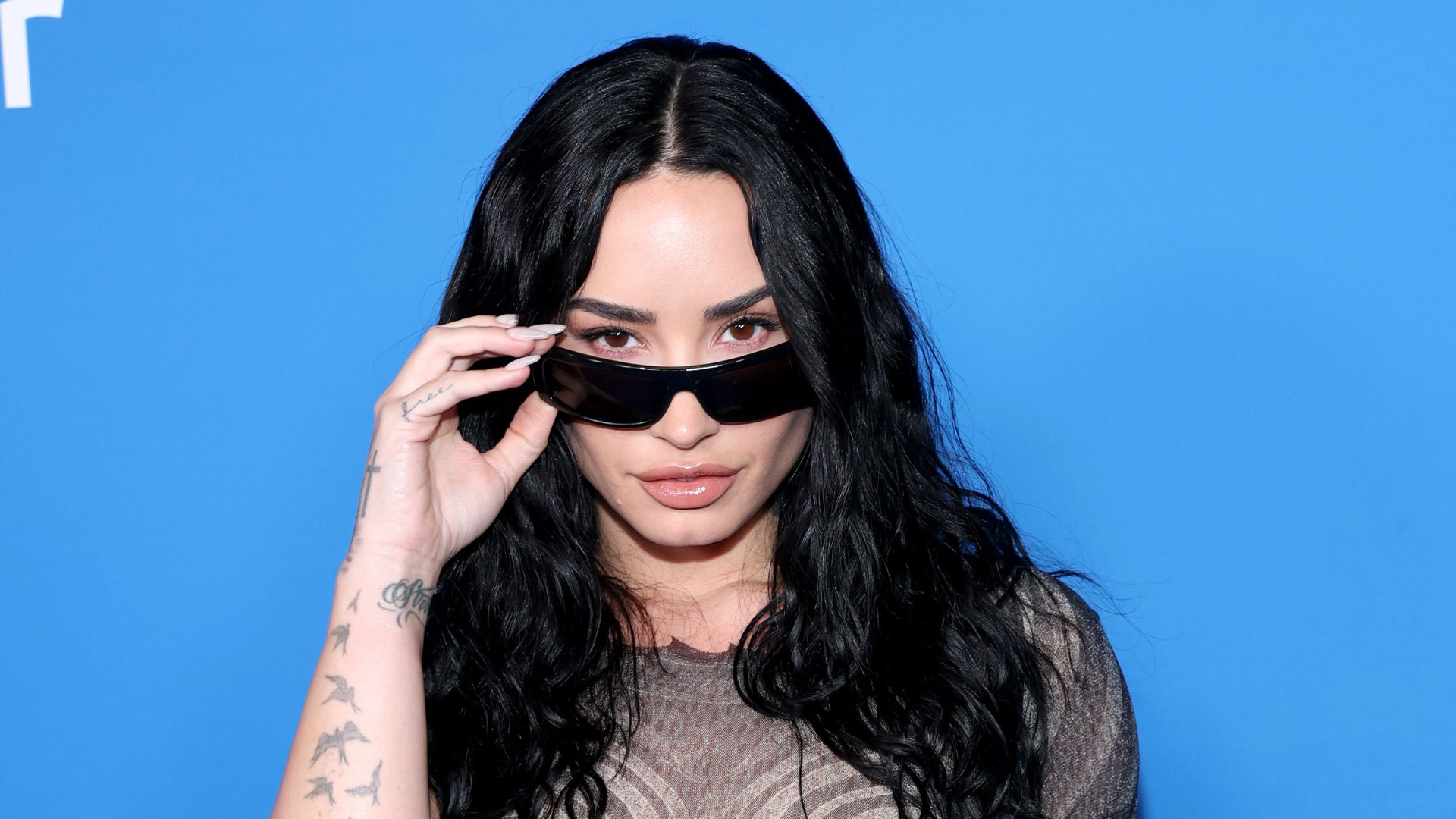Demi Lovato posa usando óculos escuros durante evento promocional antes de anunciar show em São Paulo.