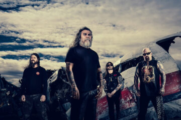 Integrantes do Slayer posam diante de destroços de avião durante divulgação do show de 40 anos do álbum Reign in Blood.
