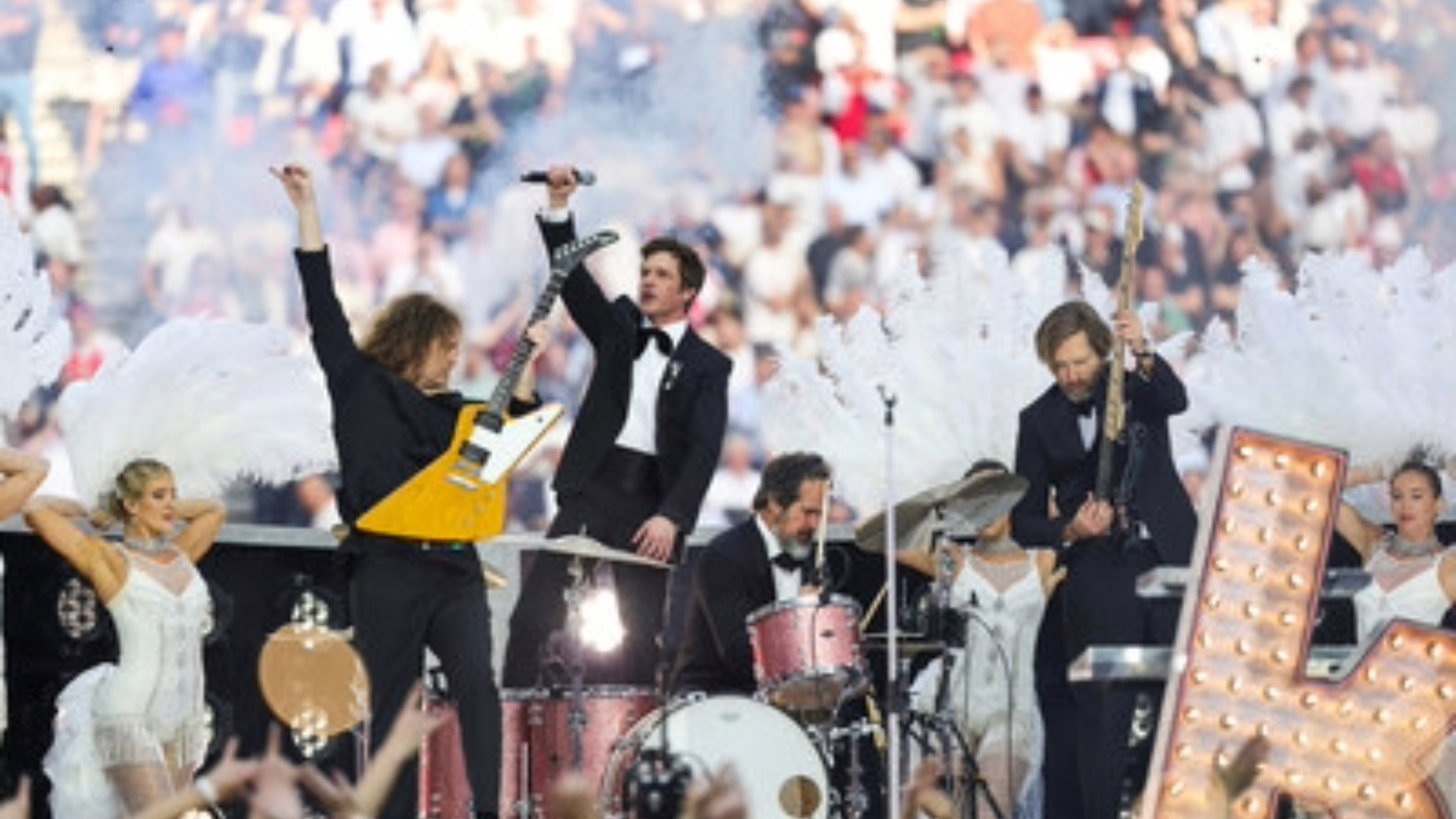 Brandon Flowers e The Killers durante apresentação na abertura da final da Champions League, acompanhados por dançarinas e produção inspirada em Las Vegas.