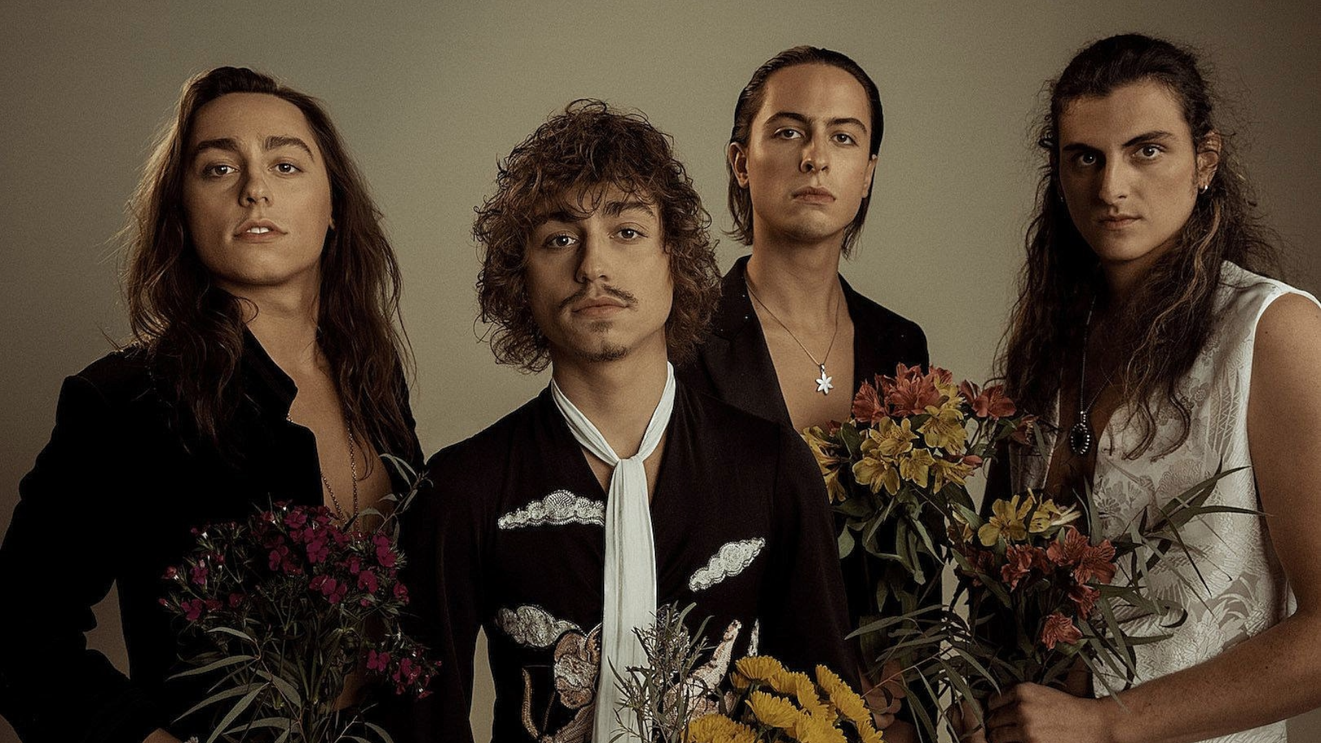 Integrantes do Greta Van Fleet posando juntos em ensaio fotográfico com flores