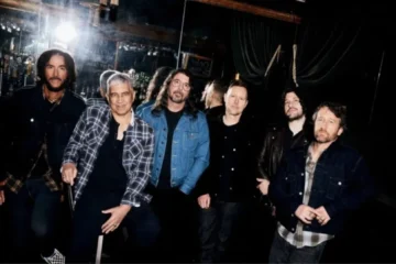 Integrantes do Foo Fighters reunidos em uma foto promocional nos bastidores, liderados por Dave Grohl.