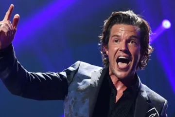 Brandon Flowers cantando durante show do The Killers com iluminação de palco