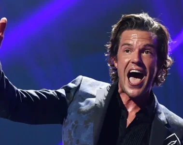 Brandon Flowers cantando durante show do The Killers com iluminação de palco
