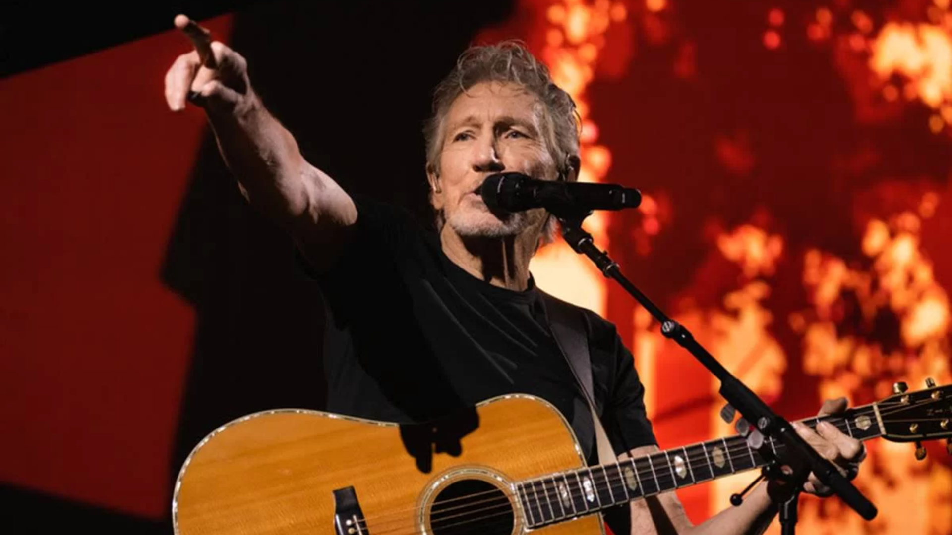 Roger Waters se apresentando ao vivo com violão durante show, integrante do Pink Floyd