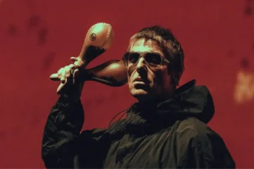 Liam Gallagher segurando suas tradicionais maracas durante apresentação. O vocalista afirmou que Be Here Now é o melhor álbum do Oasis.