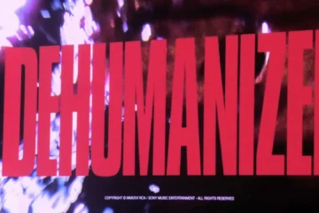 A palavra "DEHUMANIZED" aparece em letras vermelhas gigantes em uma tela durante um show do Bring Me The Horizon. Ao fundo, luzes e efeitos visuais criam uma atmosfera intensa e sombria, sugerindo o anúncio de um novo projeto da banda.
