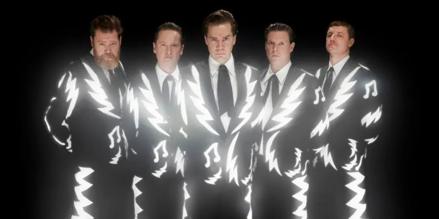 Integrantes do The Hives usando ternos preto e branco em foto promocional da banda sueca de garage rock.