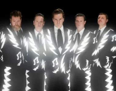 Integrantes do The Hives usando ternos preto e branco em foto promocional da banda sueca de garage rock.