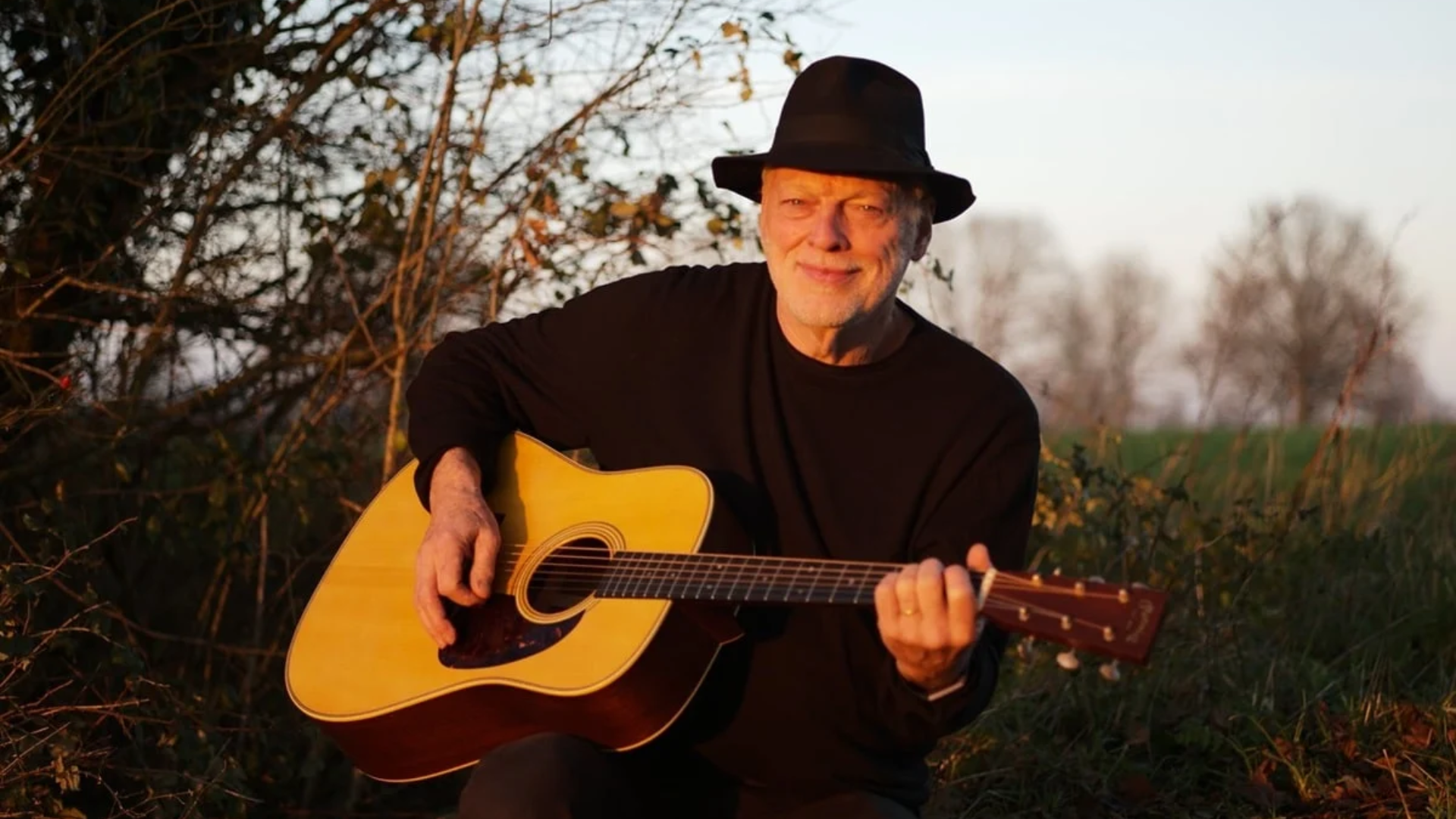David Gilmour toca violão durante sessão ao ar livre; guitarrista recomendou o álbum Blues Breakers with Eric Clapton para jovens músicos.