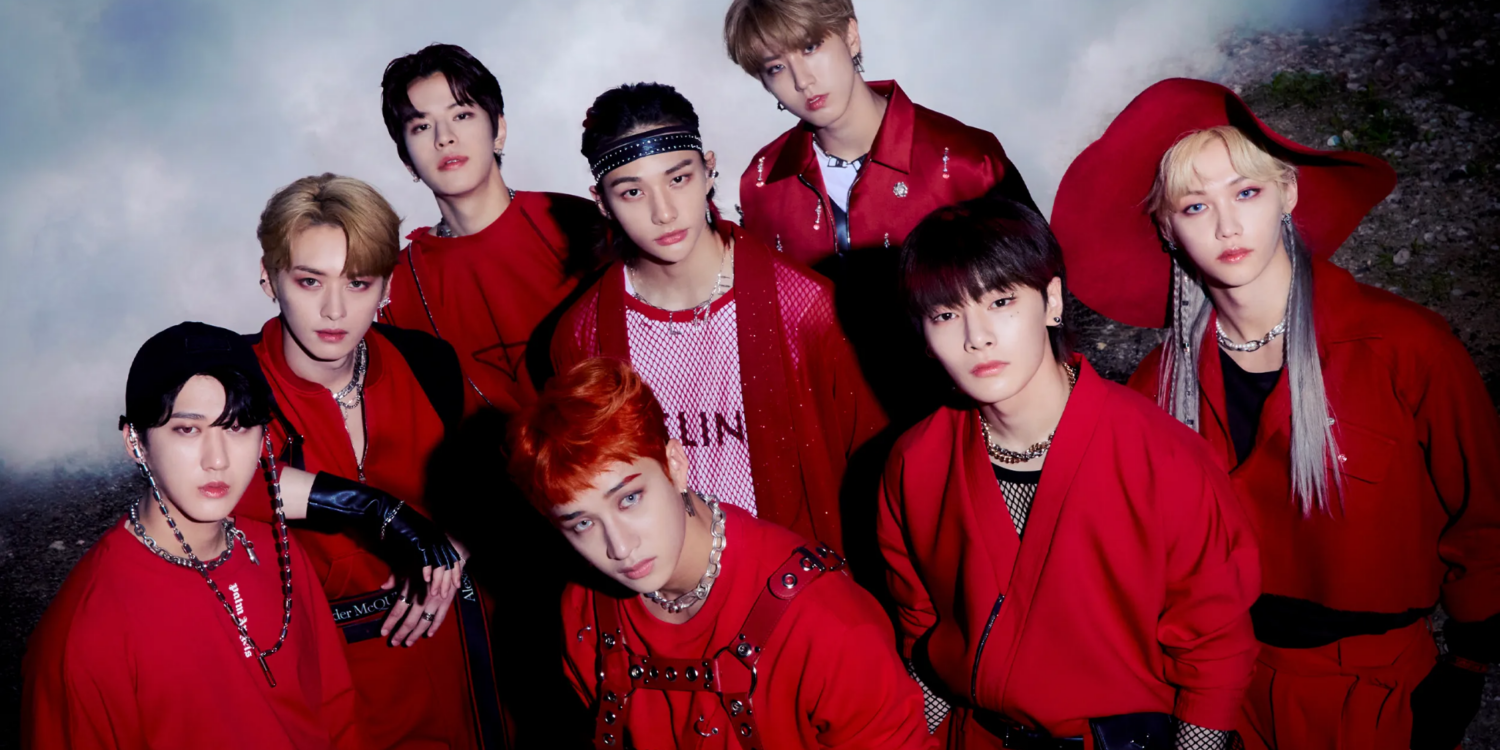 Integrantes do Stray Kids reunidos em fotografia promocional com roupas vermelhas