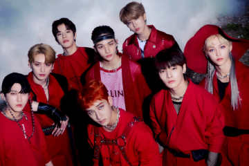 Integrantes do Stray Kids reunidos em fotografia promocional com roupas vermelhas