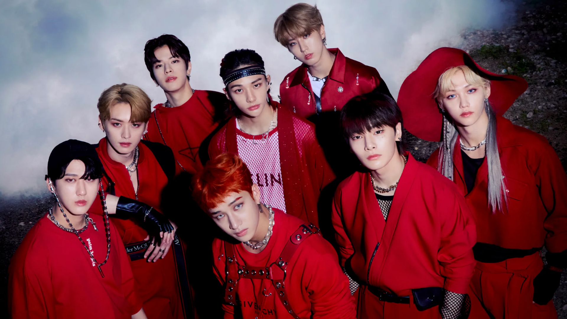 Integrantes do Stray Kids reunidos em fotografia promocional com roupas vermelhas