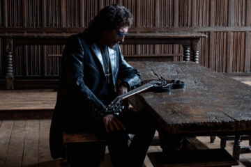 Tony Iommi sentado ao lado de sua guitarra durante a divulgação do álbum From The Dark