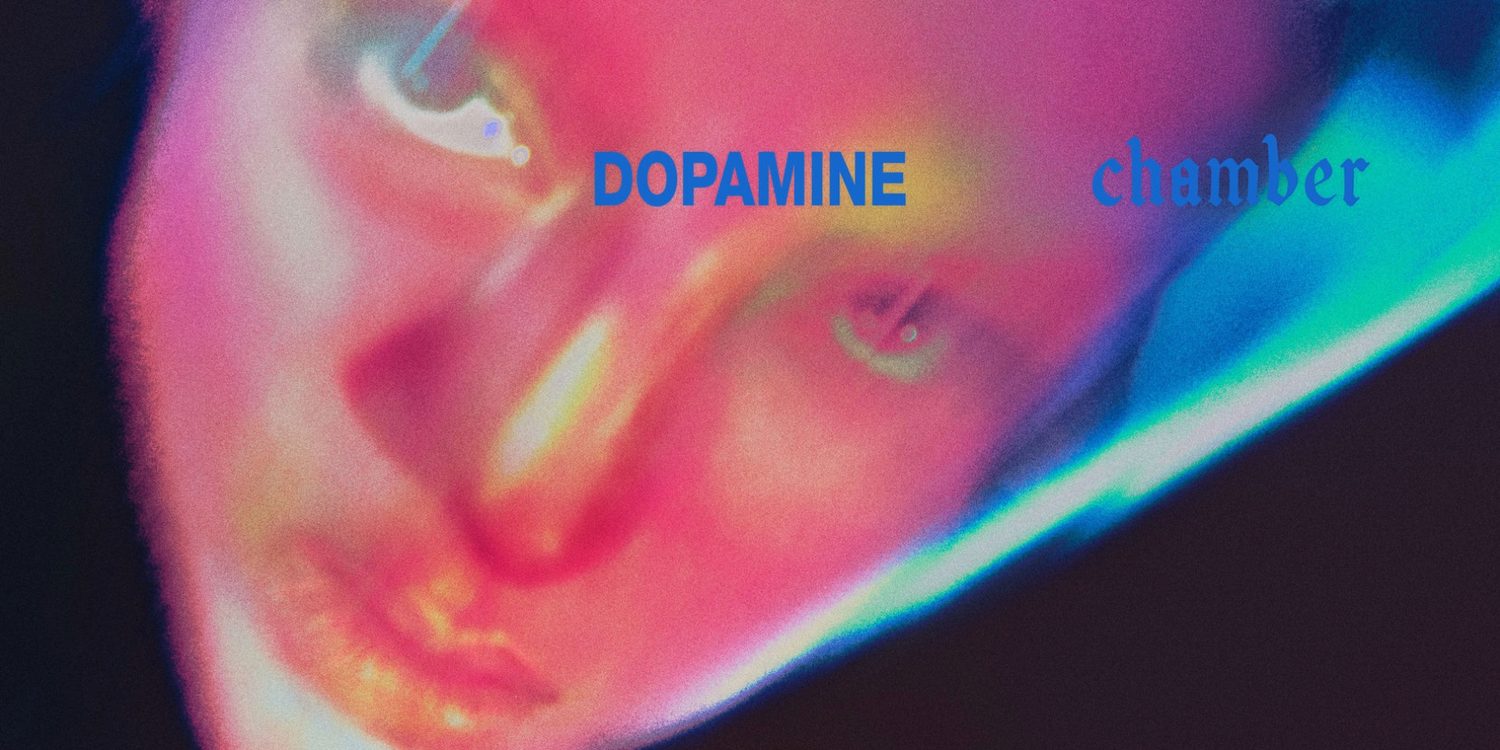 Capa do álbum Dopamine Chamber, do Fontaines D.C., com rosto em close iluminado por tons de rosa e azul e o título do disco.